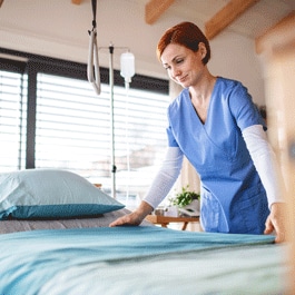nurse putting linen on hospital bed